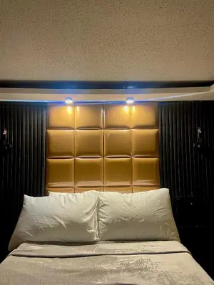 a bed with a large headboard with lights above it at IV’s Condo w/ Netflix and Wi-Fi in Cainta