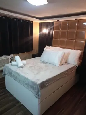 a bedroom with a large bed with white pillows at IV’s Condo w/ Netflix and Wi-Fi in Cainta