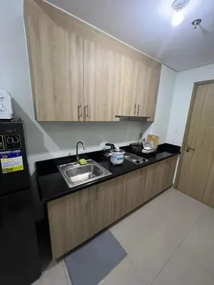 a kitchen with wooden cabinets and a sink and a refrigerator at SHORE TOWER 1 Staycation Near Mall Of Asia in Manila