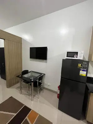 a small room with a table and a black refrigerator at SHORE TOWER 1 Staycation Near Mall Of Asia in Manila