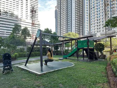 a woman is playing on a swing set in a park at Flair Towers STUDIO ROOMS Staycation in Manila