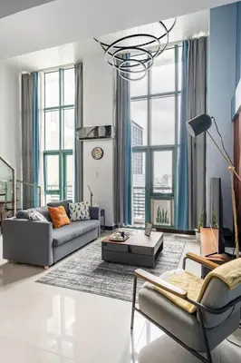 a living room with a couch and a chandelier at Stylish loft, 65 in UHDTV w Fast WiFi + Pool & Gym in Manila