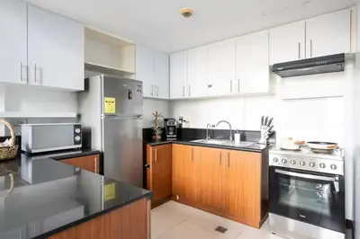 a kitchen with white cabinets and stainless steel appliances at Stylish loft, 65 in UHDTV w Fast WiFi + Pool & Gym in Manila