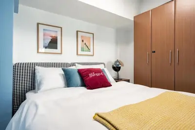 a bedroom with a white bed and a brown cabinet at Stylish loft, 65 in UHDTV w Fast WiFi + Pool & Gym in Manila