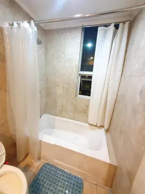 a bathroom with a tub and a toilet and a window at SAB R. CONDOTE'L SUITES in Manila