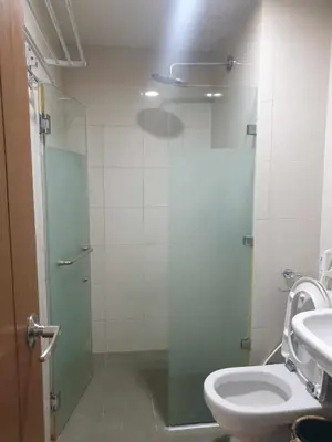 a bathroom with a toilet and a glass shower door at ETON BAYPARK MANILA by TRIPLE VIEW CONDOTEL in Manila