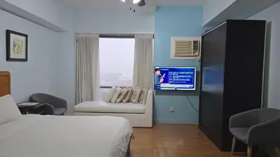 a bedroom with a bed and a couch and a tv at ETON BAYPARK MANILA by TRIPLE VIEW CONDOTEL in Manila