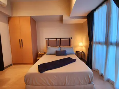 a bedroom with a large bed with blue curtains at 7 BGC Shopping Haven Steps Away from Uptown Mall and Mitsukoshi Mall FREE Parking with Washer in Manila