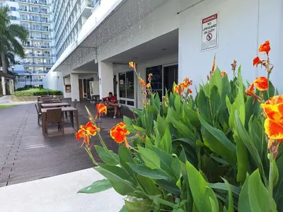 a patio with tables and flowers in front of a building at Best staycation at Shell residences in MOA complex in Manila