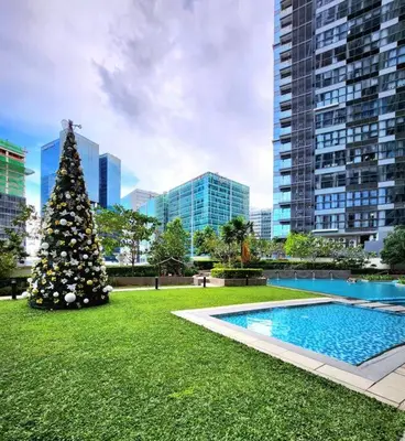 a christmas tree sitting in the grass next to a pool at Cosy Executive 1 BR Uptown Parksuites Ultra fast Internet in Manila