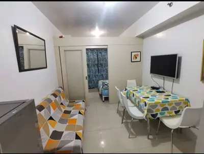 a room with a table and chairs and a tv at Sea Residences Staycation by TVANS CONDOTEL Pasay City in Manila