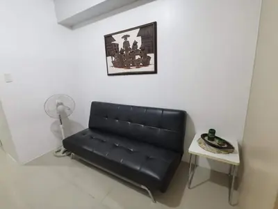 a black leather couch in a room with a table at Sea Residences Staycation by TVANS CONDOTEL Pasay City in Manila