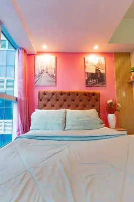 a bedroom with a large bed with pink walls at Modern 1BR in Uptown BGC in Manila