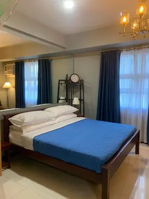 a bedroom with a large bed with a clock on the wall at 101 Newport condo in Pasay near airport in Manila