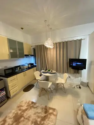 a living room with a table and chairs and a kitchen at Comfy Artsy Studio in BGC in Manila