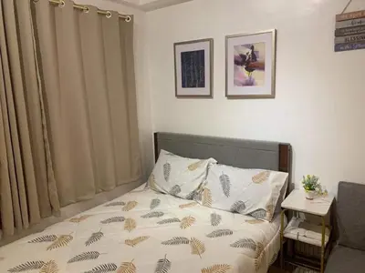 a small bedroom with a bed with a bedspread with leaves at Comfy Artsy Studio in BGC in Manila