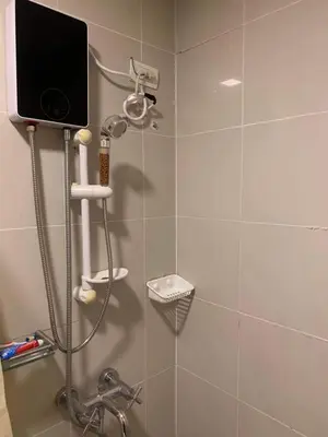 a bathroom with a shower with a television on the wall at Comfy Artsy Studio in BGC in Manila