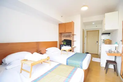 a hotel room with two beds and a table at R'Holistay Grace Taguig Fast Wifi Self Check In in Manila
