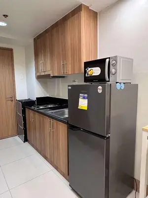 a kitchen with a stainless steel refrigerator and wooden cabinets at Shore Residences MOA by darpm in Manila