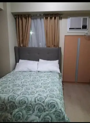 a bedroom with a bed with a green comforter at Transient Near Airport by Rqui in Manila