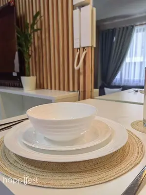 a white bowl on a stack of plates on a table at Happirest at Shore 3 Residences with Balcony, Mall of Asia in Manila