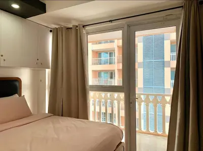 a bedroom with a bed and a large window at Luxury 1BR Unit with Pool at Venice Luxury Residences, Tower Domenico, McKinley Hill, Taguig City in Manila