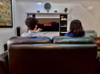 a man and woman sitting on a couch watching tv at Luxury 1BR Unit with Pool at Venice Luxury Residences, Tower Domenico, McKinley Hill, Taguig City in Manila