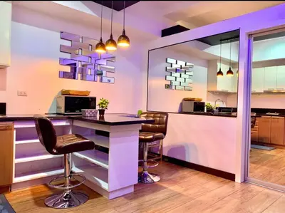 a kitchen with a bar with chairs and purple lighting at Luxury 1BR Unit with Pool at Venice Luxury Residences, Tower Domenico, McKinley Hill, Taguig City in Manila