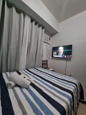 a bedroom with a bed with a television in it at Macks Awesome Place 204 NetflixFastWifi in Manila
