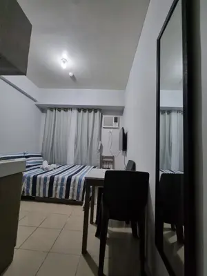 a bedroom with a bed and a table and a mirror at Macks Awesome Place 204 NetflixFastWifi in Manila