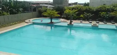 a large blue swimming pool with palm trees in it at Night Blink Staycation And Rentals in Cainta
