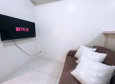 a living room with a couch and a tv on the wall at Sweden's Tiny Home, Studio Unit Condo in Manila