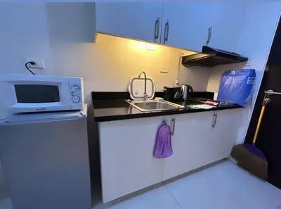 a small kitchen with a microwave and a sink at Sweden's Tiny Home, Studio Unit Condo in Manila