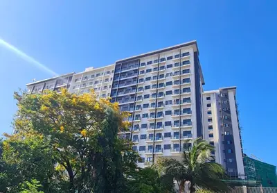 a tall building with trees in front of it at Spring Residences Scandinavian 2 bedrooms with balcony Near NAIA in Manila