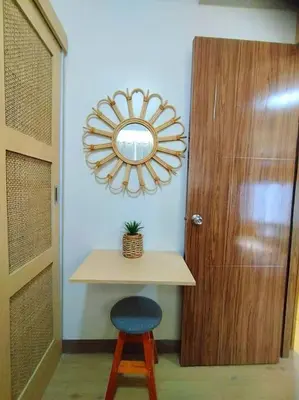 a mirror over a table next to a door with a stool at Spring Residences Scandinavian 2 bedrooms with balcony Near NAIA in Manila