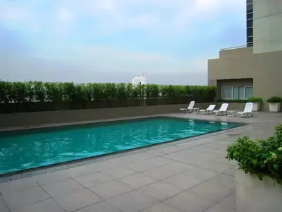 a swimming pool with lounge chairs next to a building at BGC Private Apartments in Manila