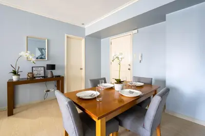 a dining room with a wooden table and chairs at BGC Private Apartments in Manila