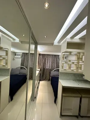 a room with two beds and a desk in a room at Grand Riviera Suits in Manila
