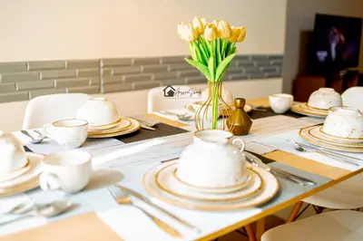 a table with plates and cups and a vase of flowers at Aussie Shack - 2BR Modern Condo with Skyline View in Manila
