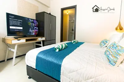 a bedroom with a bed with a television on a desk at Aussie Shack - 2BR Modern Condo with Skyline View in Manila