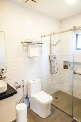 a bathroom with a toilet and a glass shower at Orchard Tiny Home - Golf Course Pet Friendly Lot in Baluctot