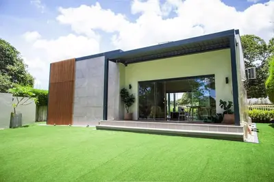 a house with a green lawn in front of it at Orchard Tiny Home - Golf Course Pet Friendly Lot in Baluctot