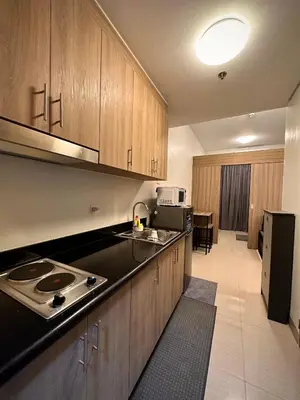 a kitchen with wooden cabinets and a stove top oven at Victoria’s Place in Manila