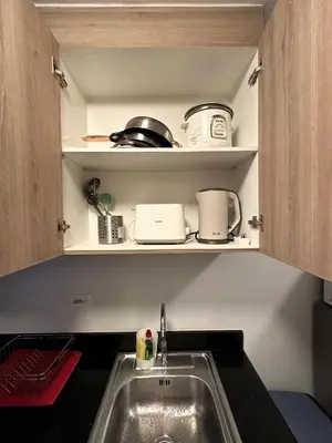 a kitchen with a sink and a shelf with pots and pans at Victoria’s Place in Manila