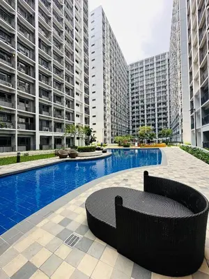 a black bench sitting in the middle of a pool with tall buildings at Victoria’s Place in Manila