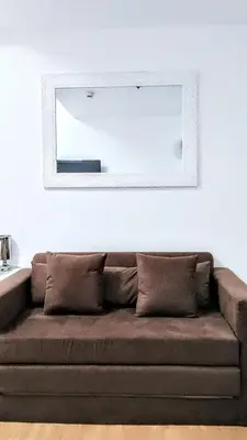 a mirror on a white wall above a couch at ROARI Portovita Towers Scandinavian Studio Unit in Manila