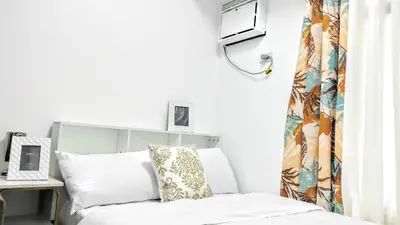a bedroom with a bed and a desk with a laptop at ROARI Portovita Towers Scandinavian Studio Unit in Manila