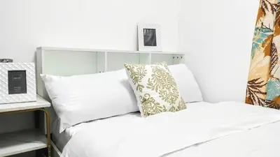 a bed with white sheets and a pillow on it at ROARI Portovita Towers Scandinavian Studio Unit in Manila