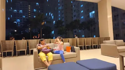 two women sitting on a couch in a building at EZStays Shore Residences in Manila