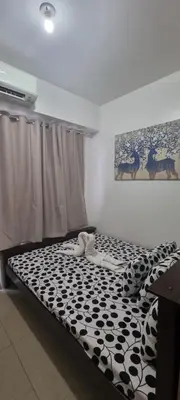 a bedroom with a black and white comforter on a bed at EZStays Shore Residences in Manila
